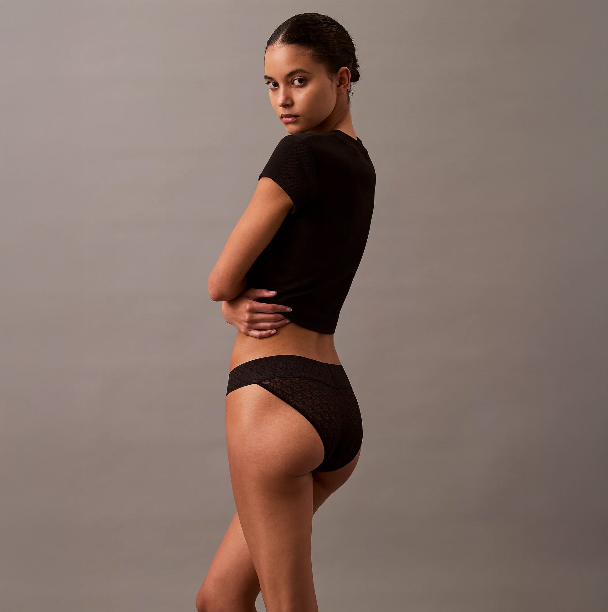 Calvin Klein ICON LOGO Low Rise Womens Bikini Briefs Black side view on model, showcasing semi-sheer finish and logo pattern.