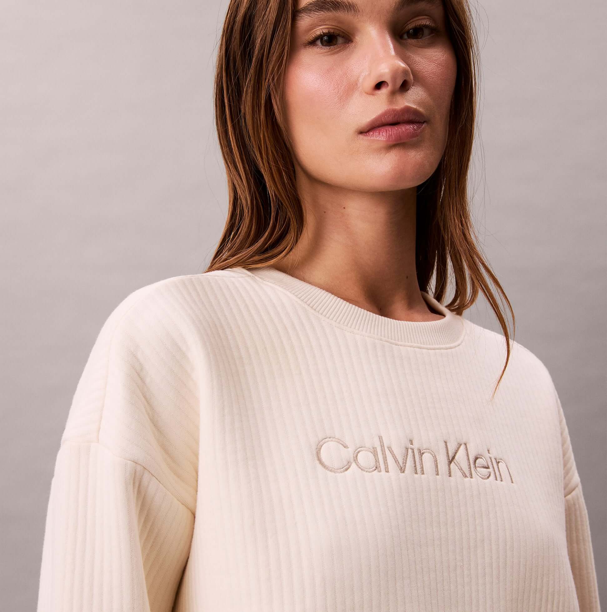 Calvin Klein LS QUILTED SWTSHIRT Womens Sweatshirts Ivory close-up view of model wearing sweatshirt with logo detail.