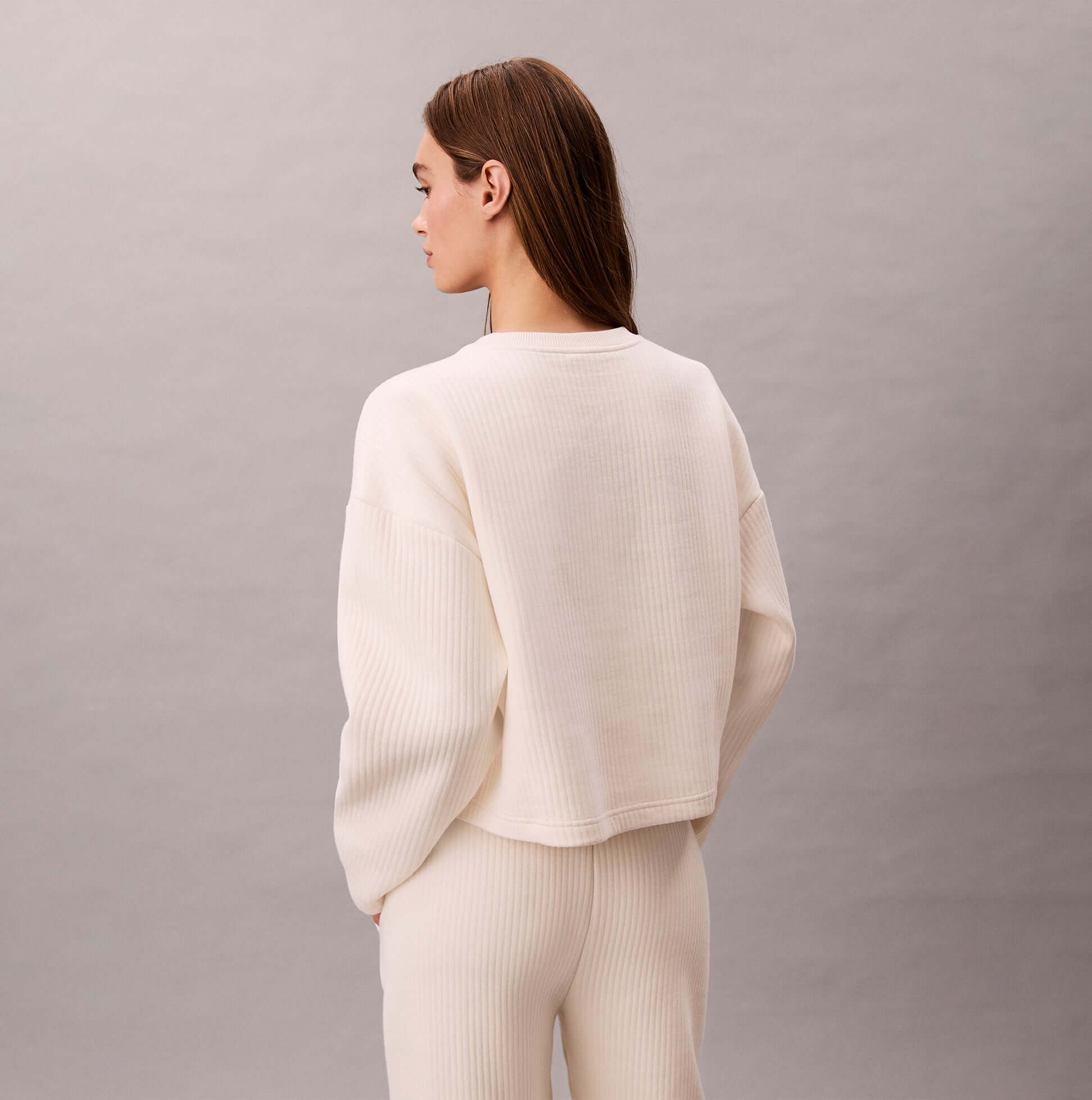 Calvin Klein LS QUILTED SWTSHIRT Womens Sweatshirts Ivory back view on model, showcasing its soft fabric and relaxed fit.