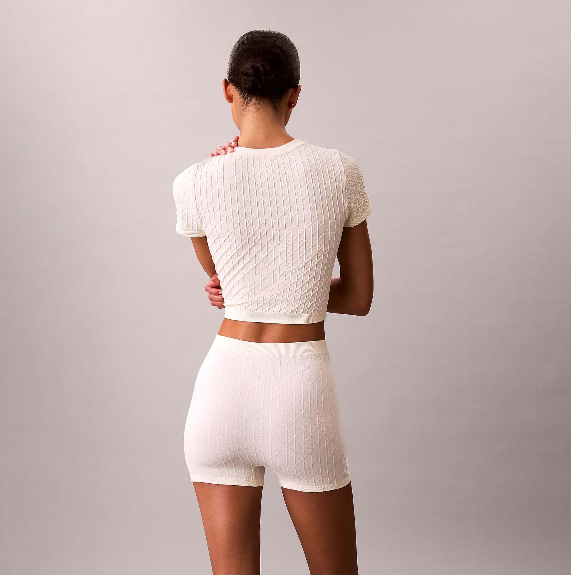 Calvin Klein SEAMLESS TEE Womens Printed CK Knit T-Shirt Ivory back view model wearing the top with matching shorts.
