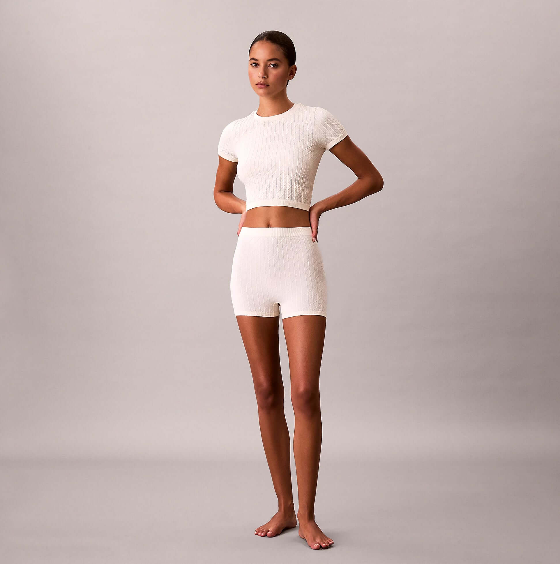 Calvin Klein SEAMLESS TEE Womens Printed CK Knit T-Shirt Ivory front view modeled by a woman wearing matching shorts.