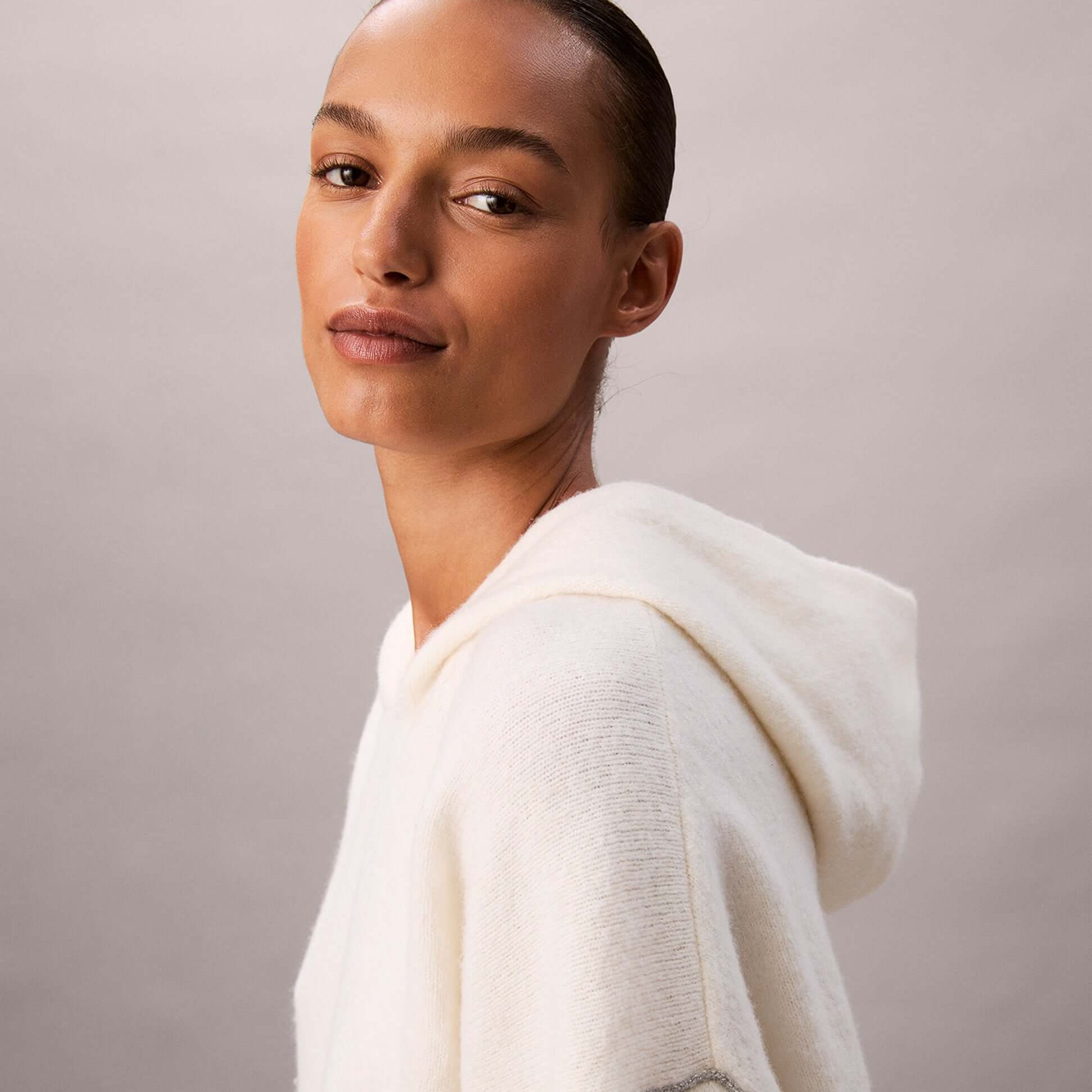 Calvin Klein PLUSH HOODIE. Womens Ivory, side view of model showcasing the soft fabric and hood details.