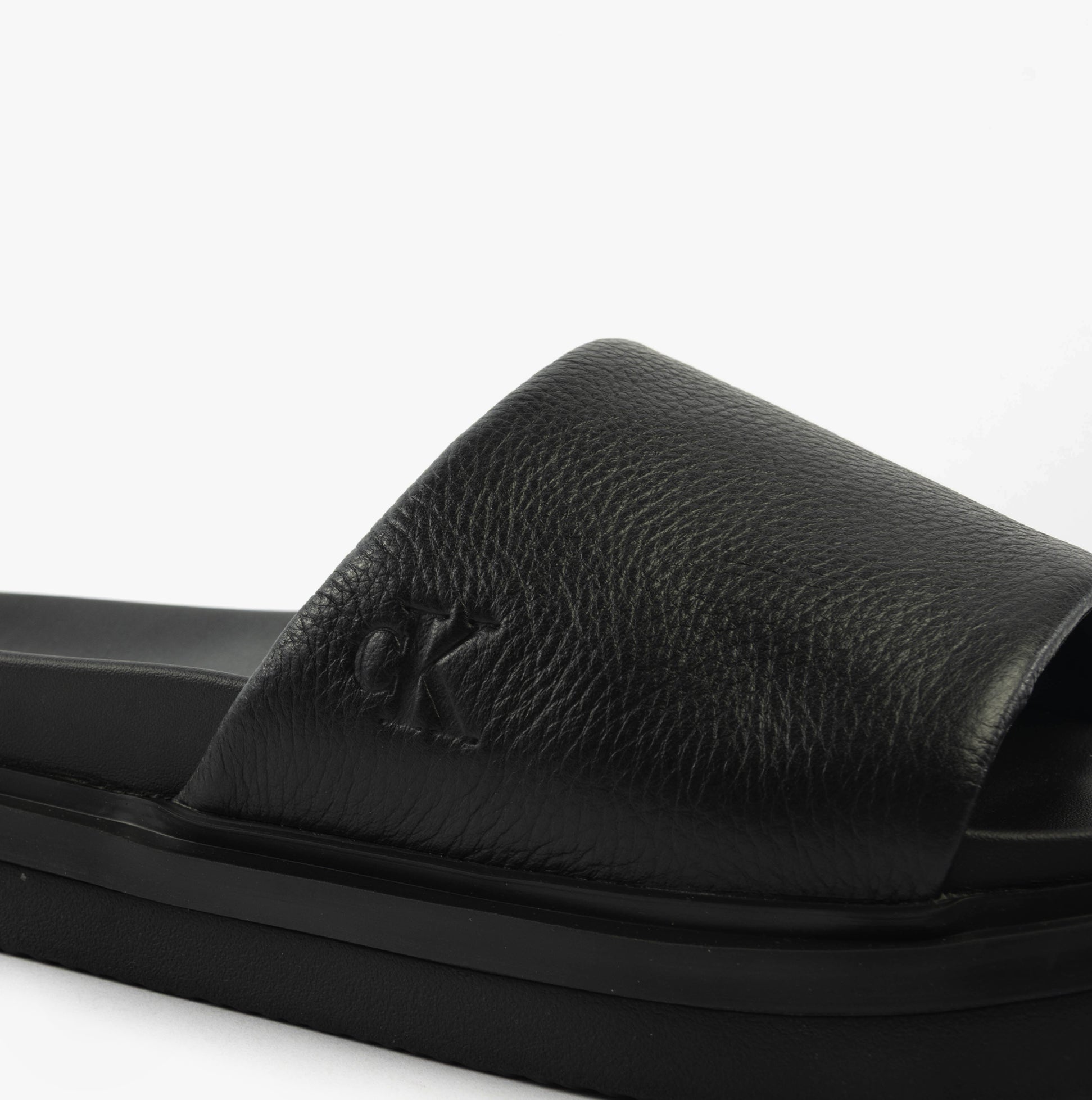 Calvin Klein FLAT MOLDED SLIDE Mens Triple Black detail view showing leather upper and logo.
