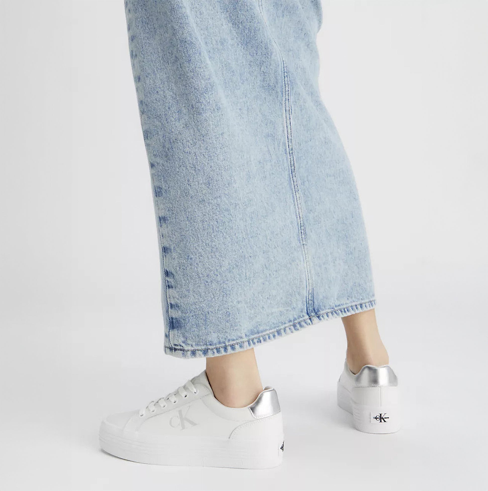 Calvin Klein BOLD VULCANISED FLATFORM Womens Trainers Bright White/Silver side view with denim skirt.