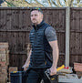 Dewalt FORCE Mens Gilet Black front view worn by a man, featuring zip closure and side pockets, suitable for work.