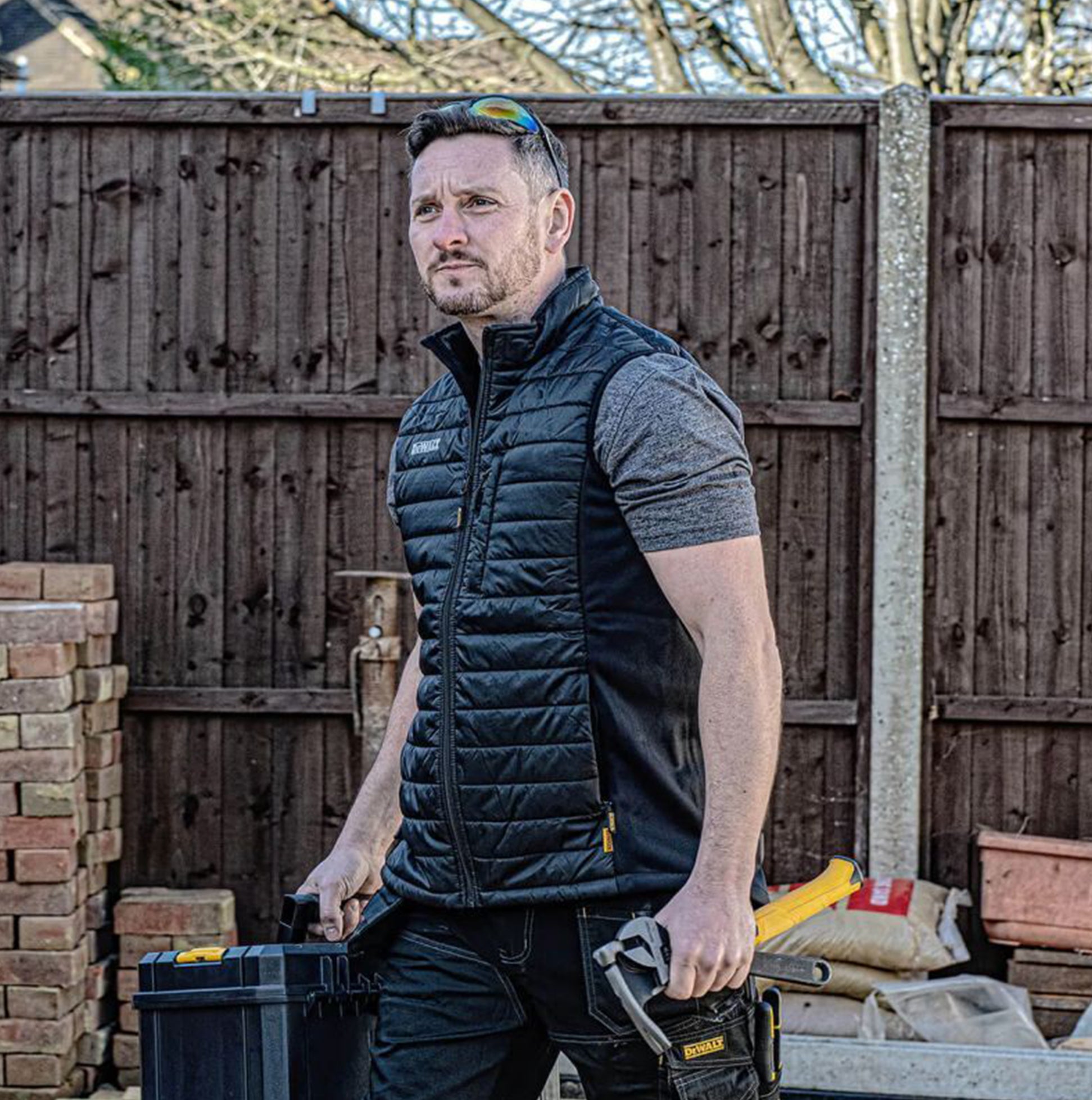 Dewalt FORCE Mens Gilet Black front view worn by a man, featuring zip closure and side pockets, suitable for work.