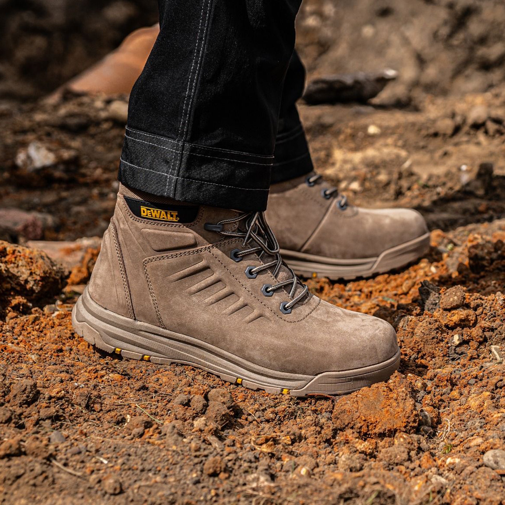 Dewalt LIMA Mens Boots Stone side view on rugged terrain, showcasing nubuck upper and rubber sole for safety and comfort.