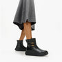 FitFlop F-MODE SQUARE-RING LEATHER FLATFORM Ladies Ankle Boots Black side view on model wearing a grey skirt