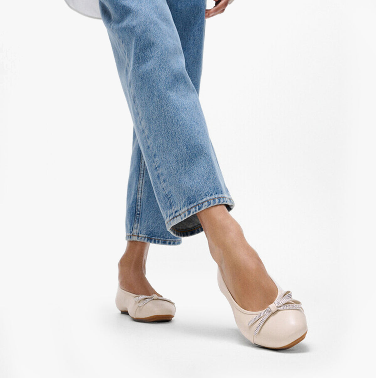 FitFlop DELICATO GLITZ-BOW LEATHER Womens Ballet Paris Beige side view showing a model wearing the shoes with denim jeans.