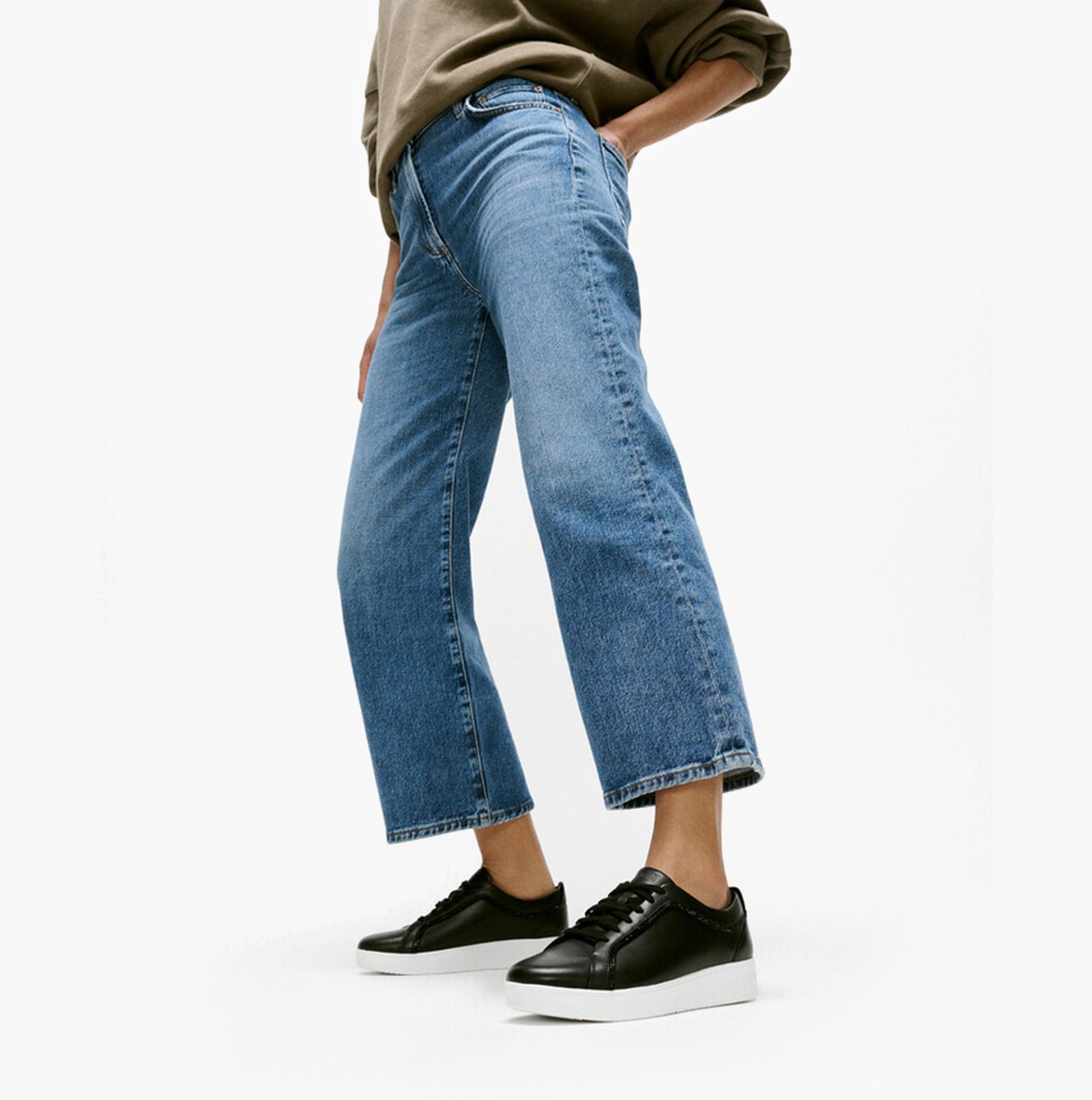 FitFlop RALLY CRYSTAL-TRIM LEATHER Womens Fashion Trainers Black worn with cropped denim jeans side view.