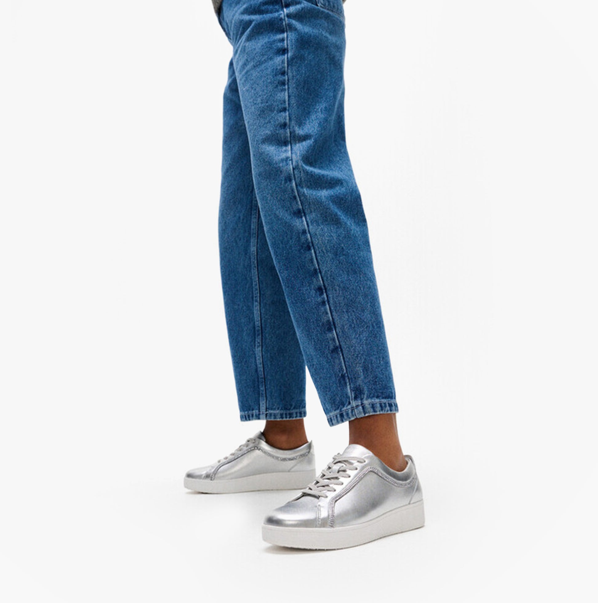 FitFlop RALLY CRYSTAL-TRIM LEATHER Womens Fashion Trainers Silver side view worn with blue jeans.