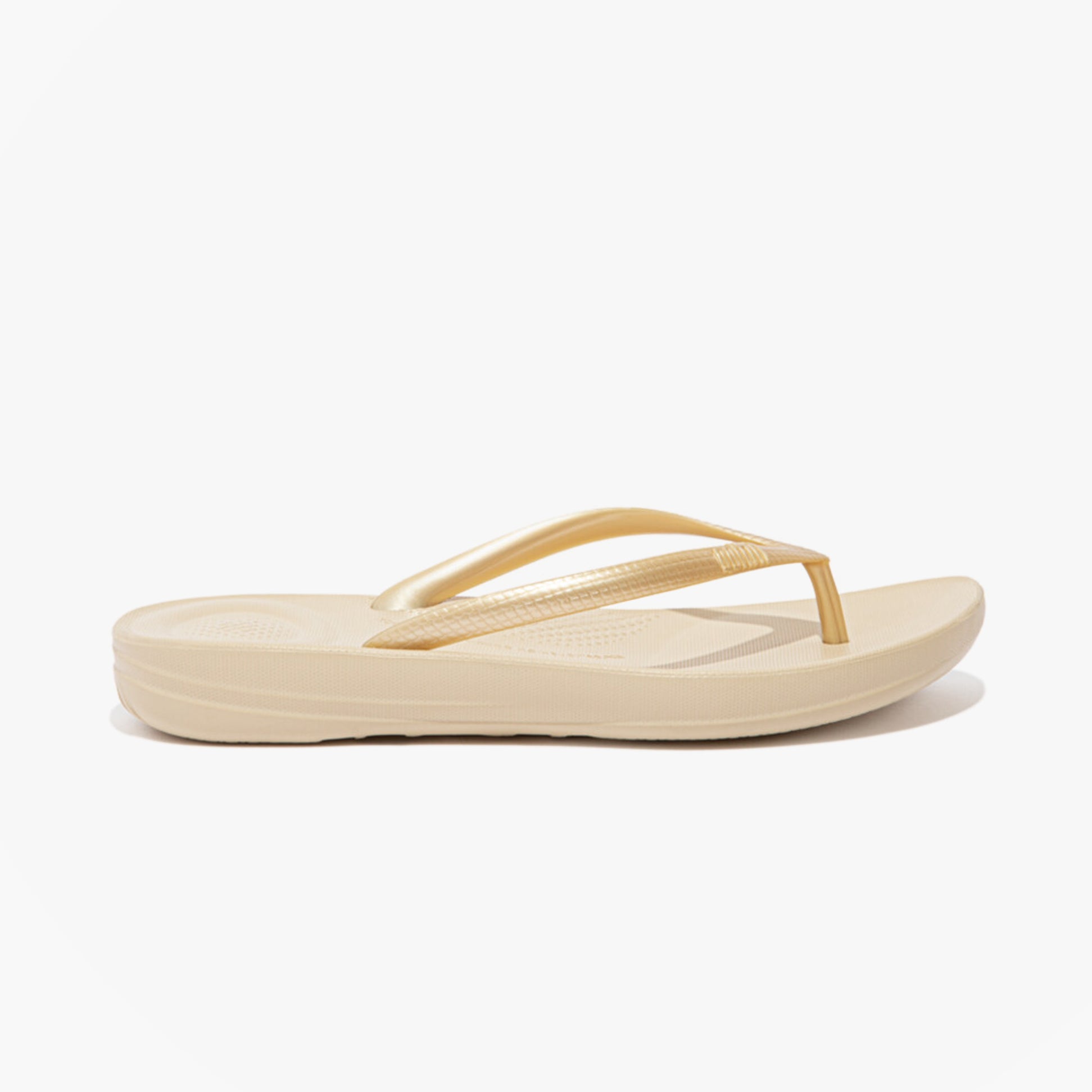 FitFlop IQUSHION Womens Flip Flops Gold side view showcasing lightweight comfort and flat sole design.