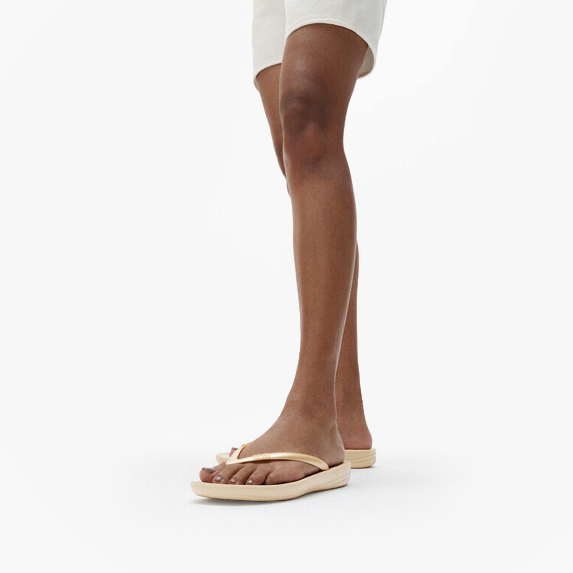 FitFlop IQUSHION Womens Flip Flops Gold side view on model's foot, showcasing the lightweight and comfortable design.