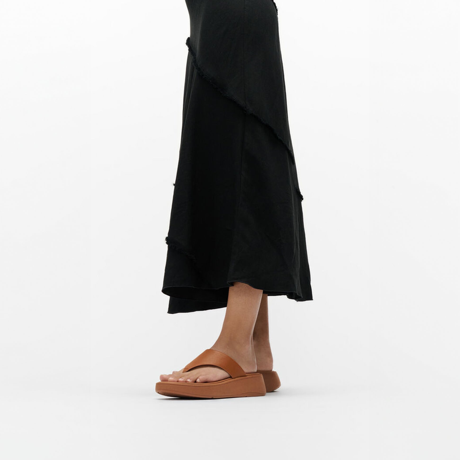 FitFlop F-MODE LEATHER FLATFORM Womens Toe Post Sandals Light Tan side view worn with a black dress, showcasing comfort and style.