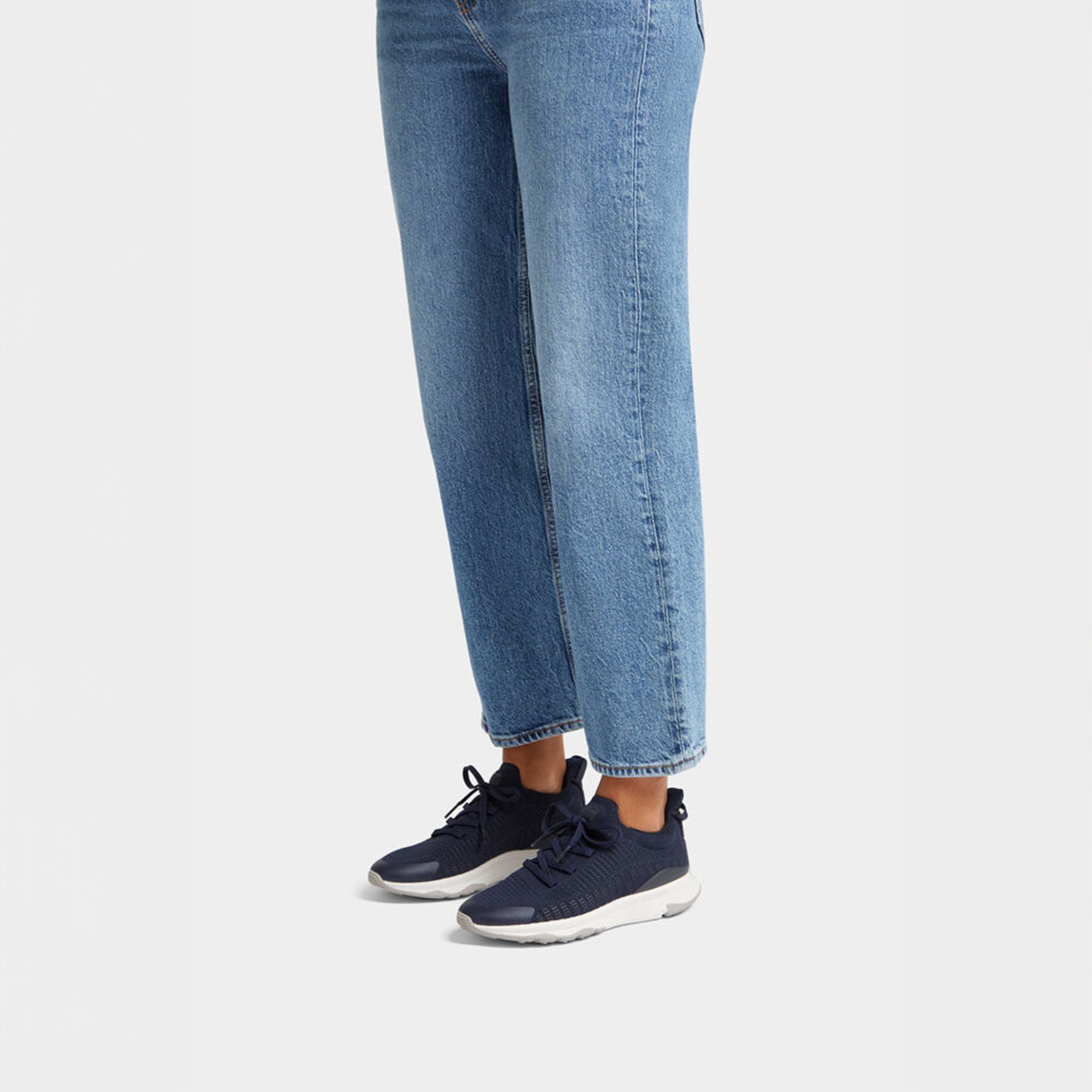 FitFlop VITAMIN FFX KNIT Womens Trainers Midnight Navy/Pewter side view with jeans showcasing casual style.