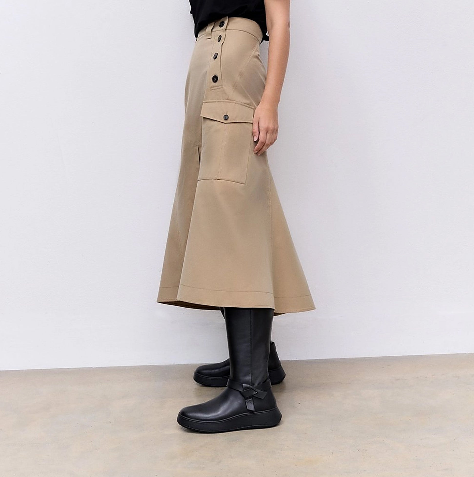 FitFlop F-MODE Womens Boots Black side view worn with a beige skirt, showcasing their sleek design and comfortable fit.