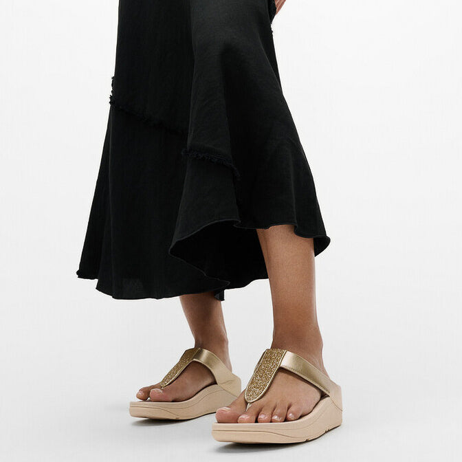 FitFlop FINO GLITTERDUST METALLIC Womens Toe Post Sandals Platino side view worn with a black dress, highlighting comfort and style.