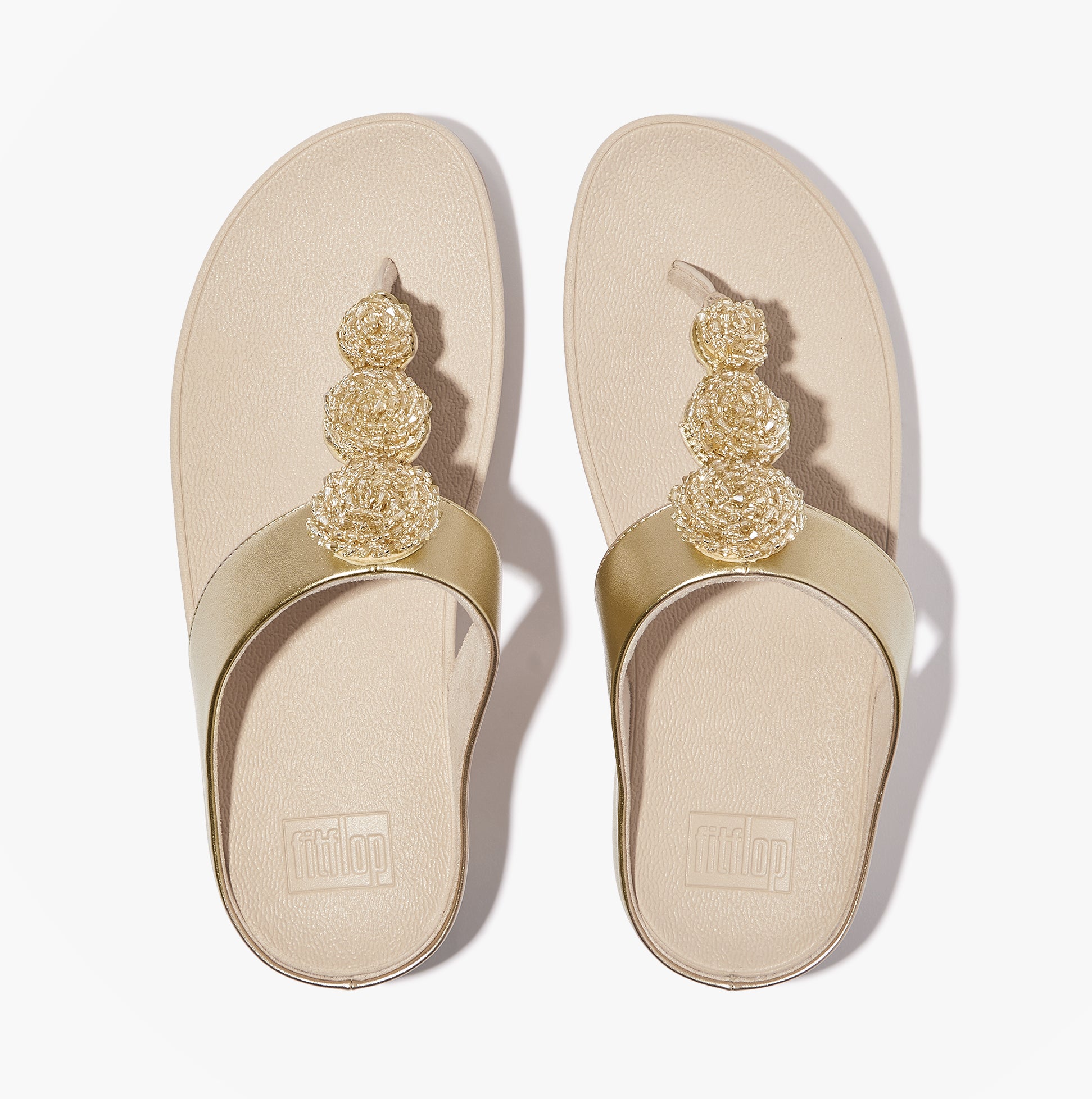 FitFlop FINO BEADIE-BUTTON Womens Toe Post Sandals Platino top view showcasing golden bead embellishments.