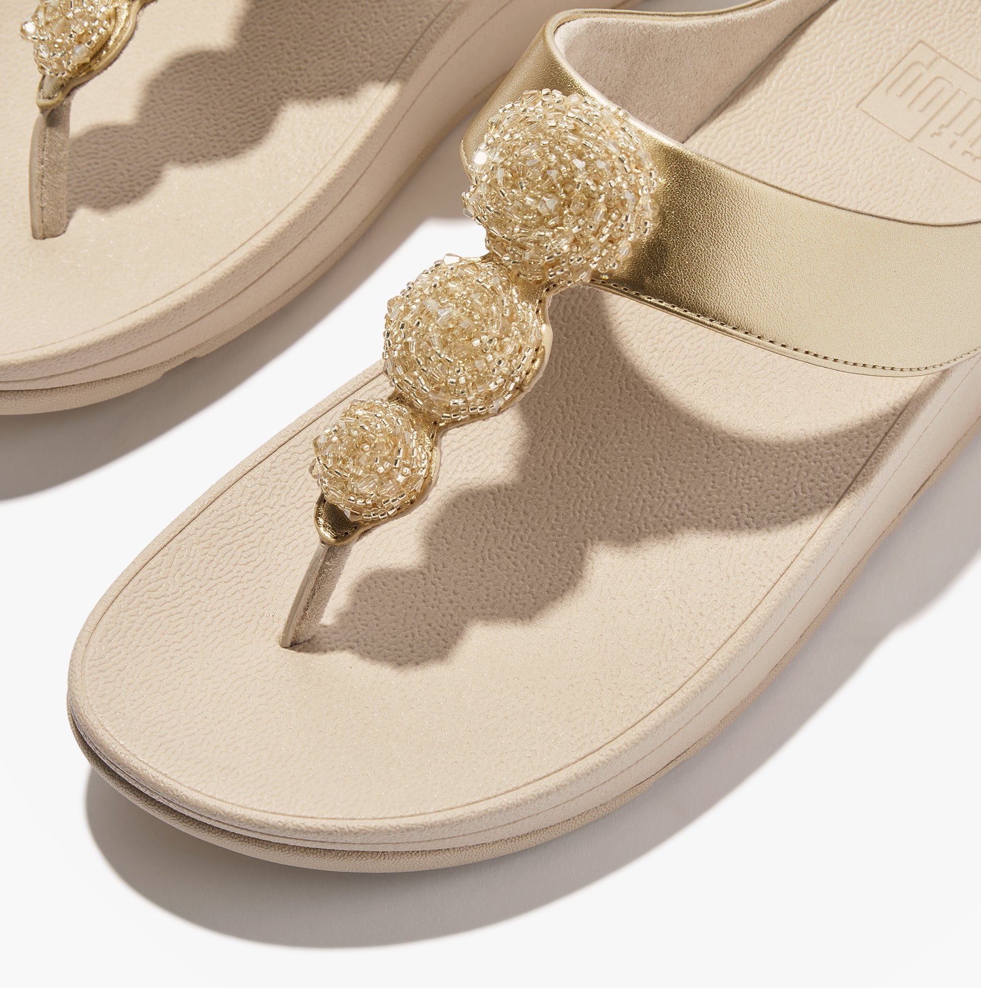FitFlop FINO BEADIE-BUTTON Womens Toe Post Sandals Platino close-up detail view with decorative beads and golden straps.