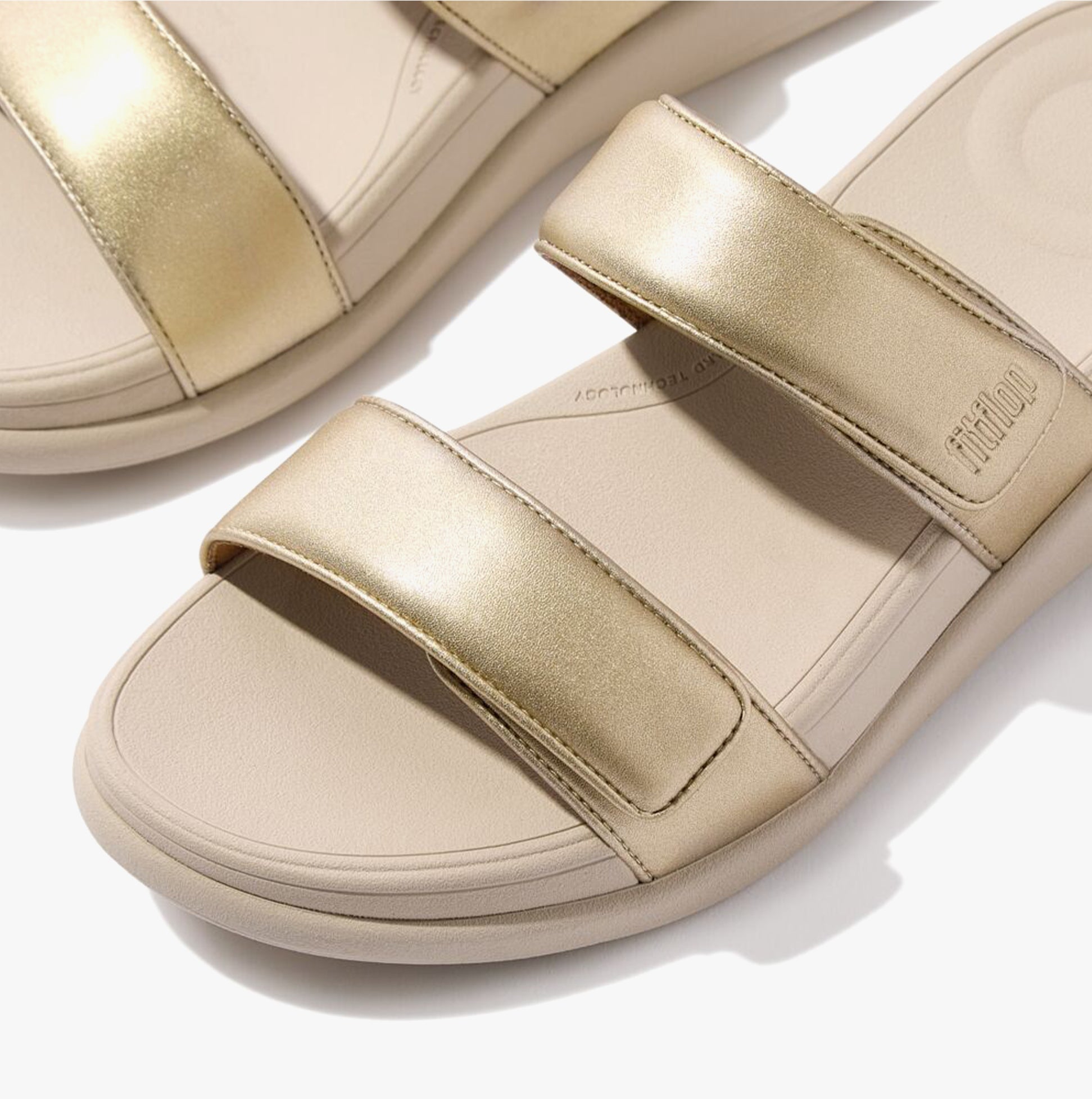 FitFlop F-MODE GO Womens Slides Platino top view showing gold leather straps and cushioned EVA sole.