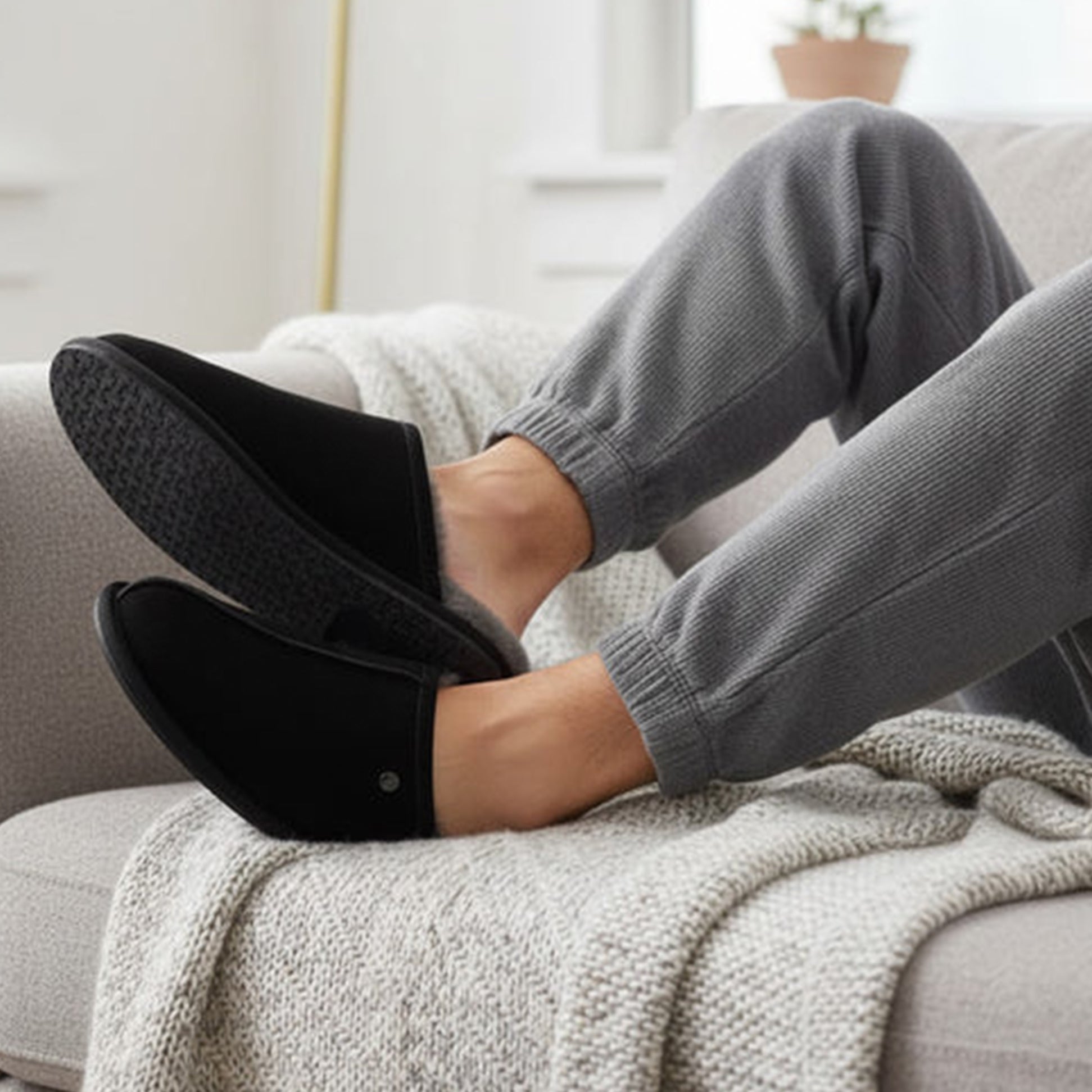 HOS Sheepskin EDWIN Mens Slippers Black, side view on feet, casual setting, relaxed style, comfortable and warm.