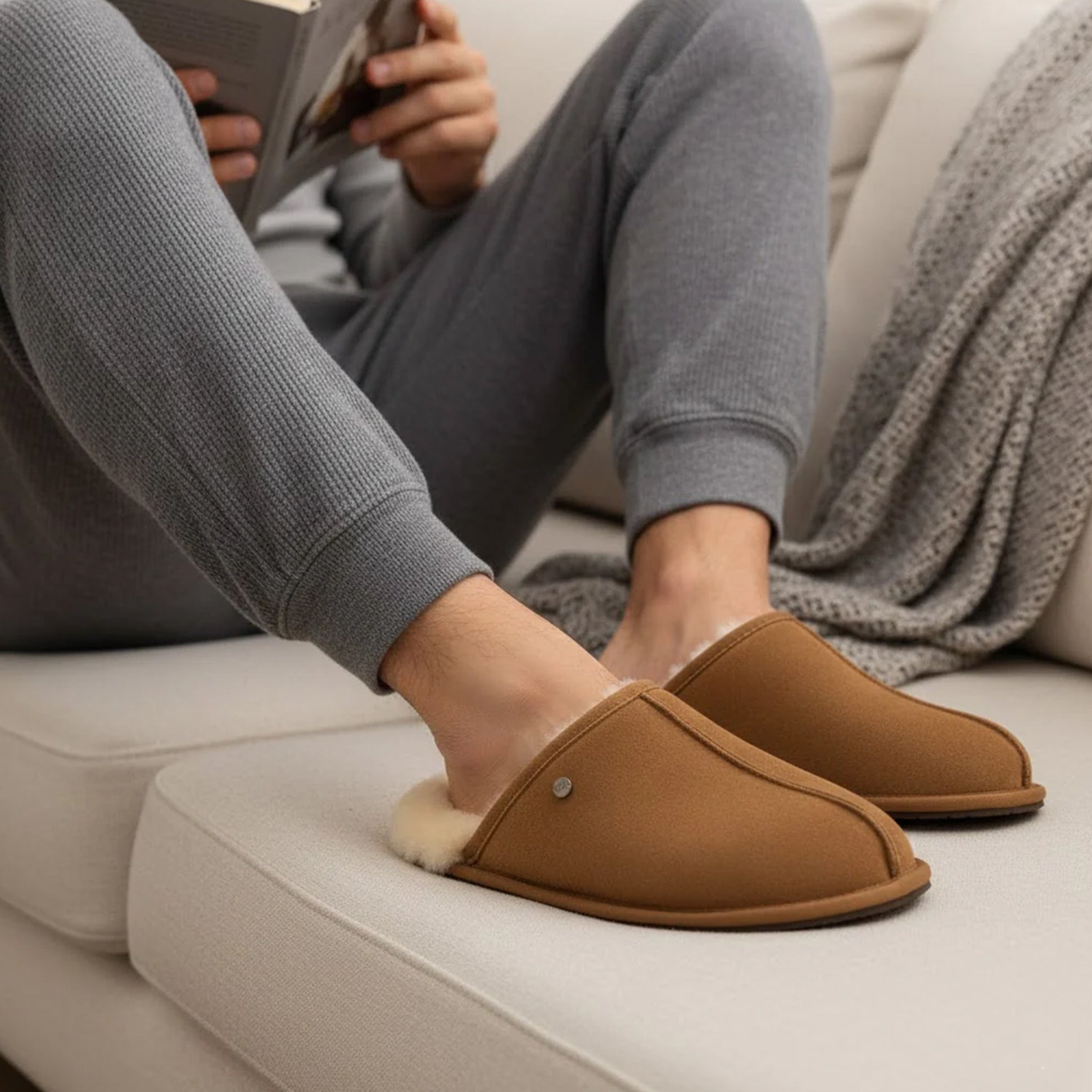 HOS Sheepskin EDWIN Mens Slippers Chestnut side view worn by a person reading on a couch.