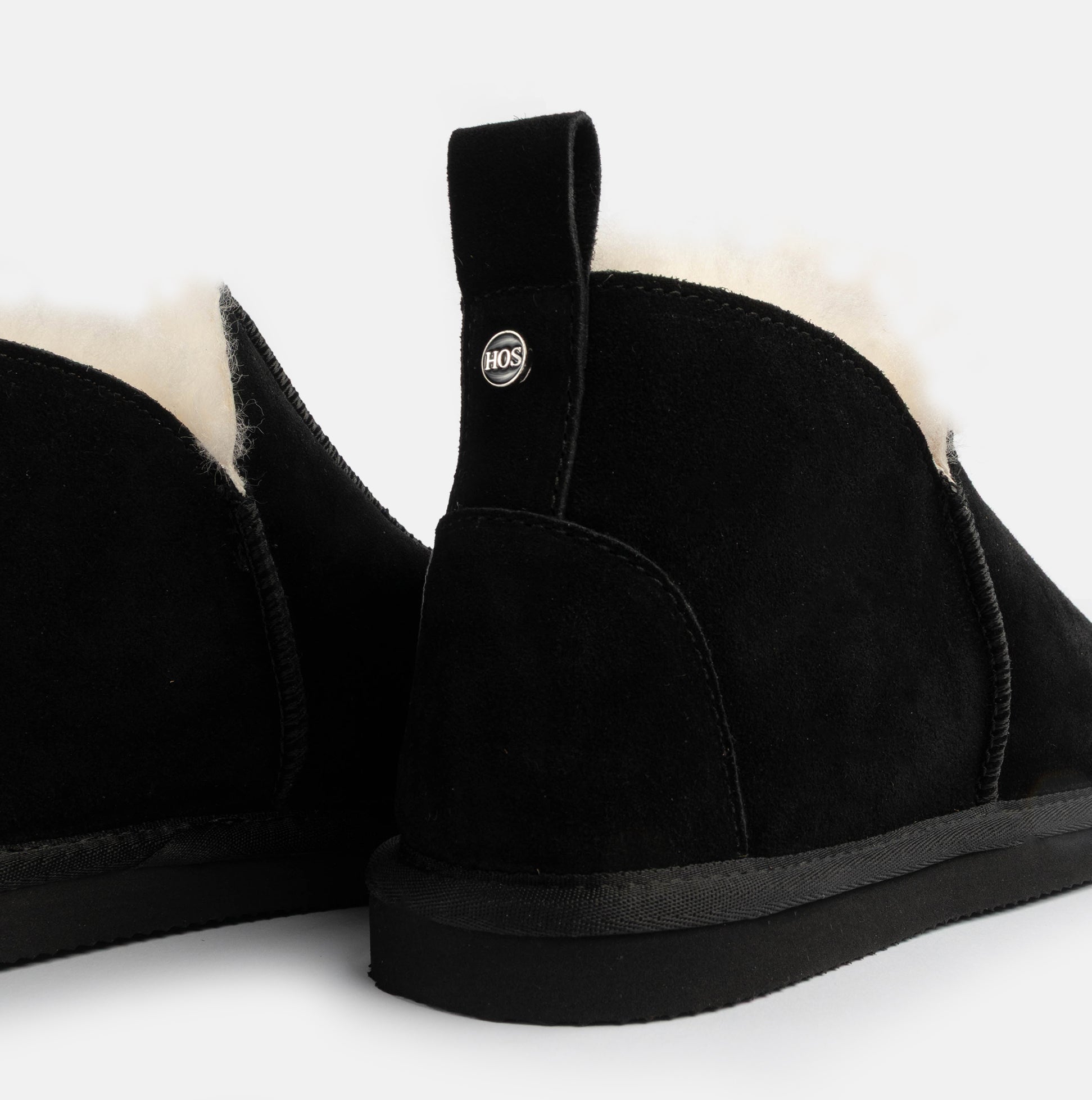 HOS Sheepskin TIA Womens Boot Slippers Black rear view with plush lining and logo detail, showcasing comfort and style.