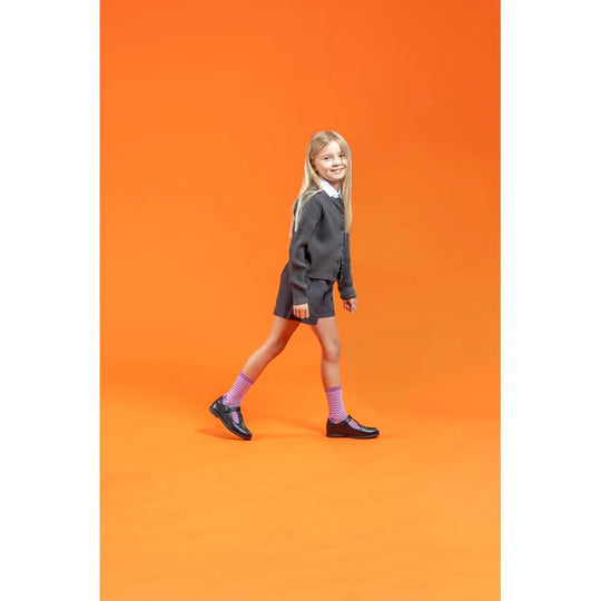 Hush Puppies BRITNEY Girls Leather School Shoes Black worn by a girl walking, side view with vibrant orange background.