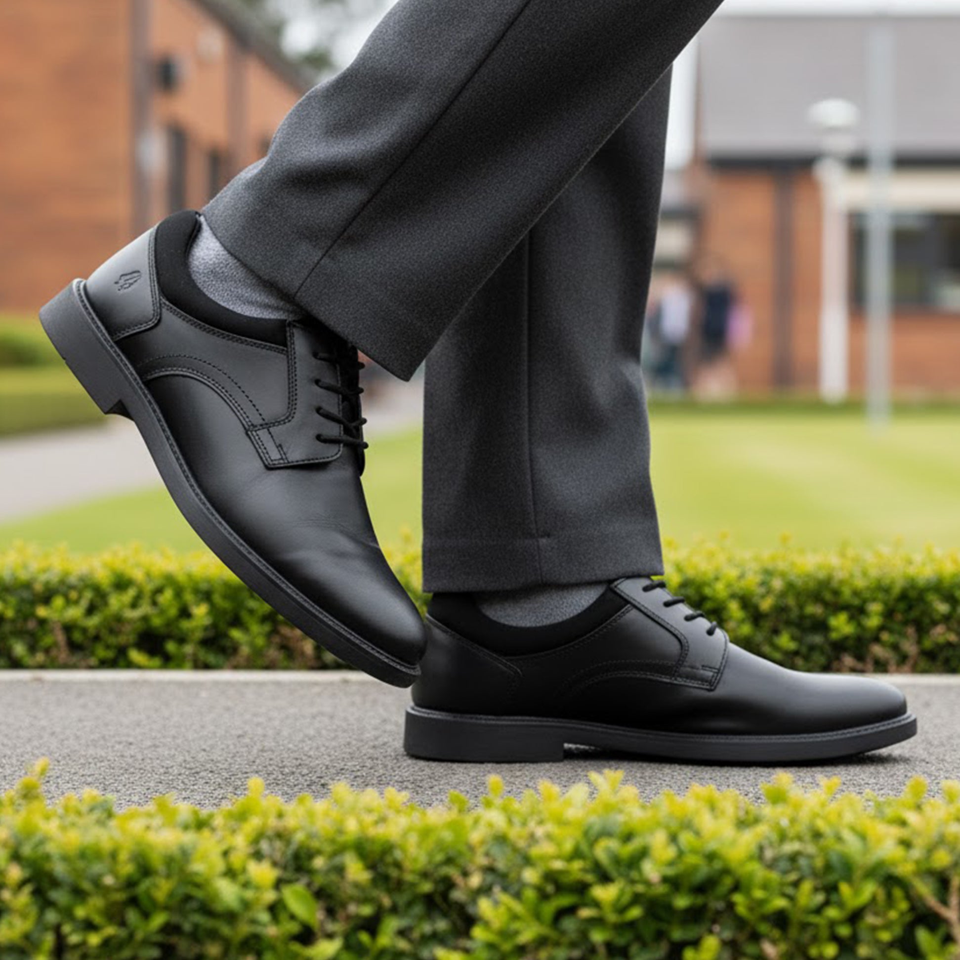 Hush Puppies TOMMY Boys Leather School Shoes Black side view worn with pants outdoors.