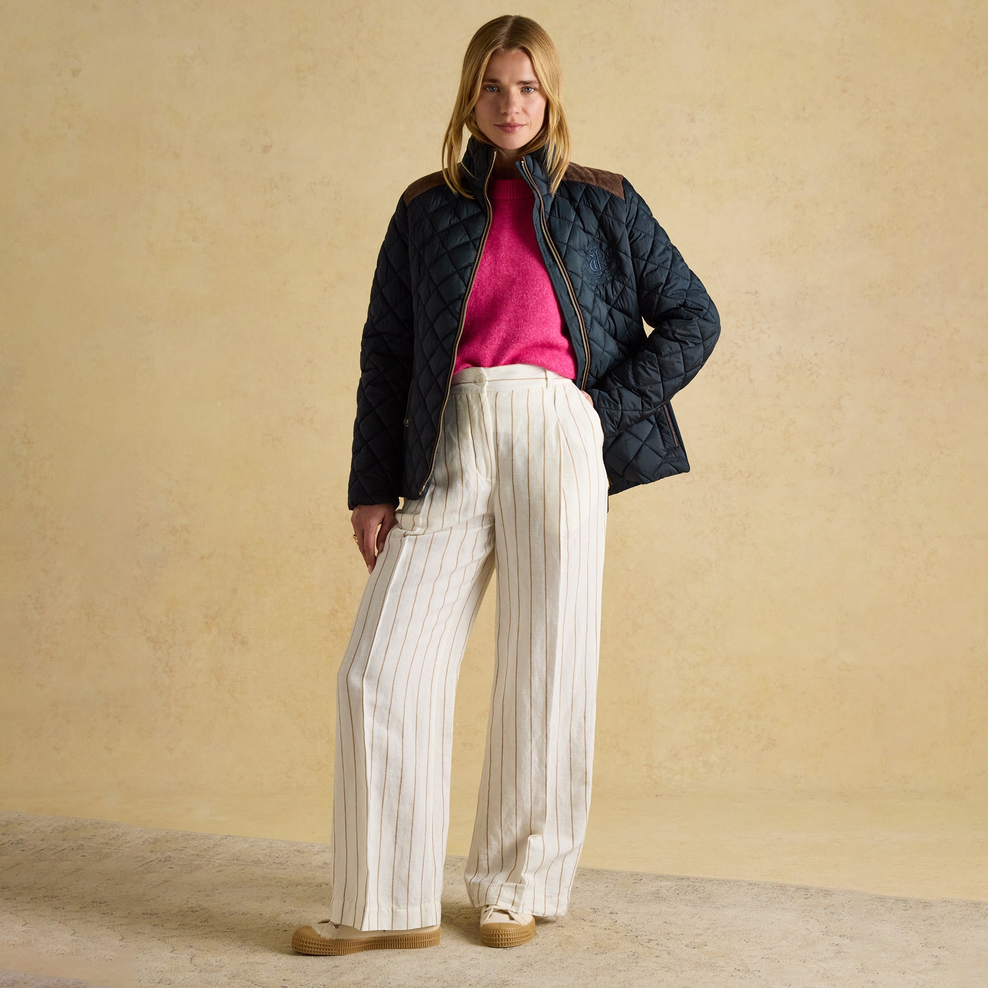 Joules BRAEMAR LUXE Womens Quilted Jacket Navy front view, model wearing quilted jacket with pink sweater and striped pants.