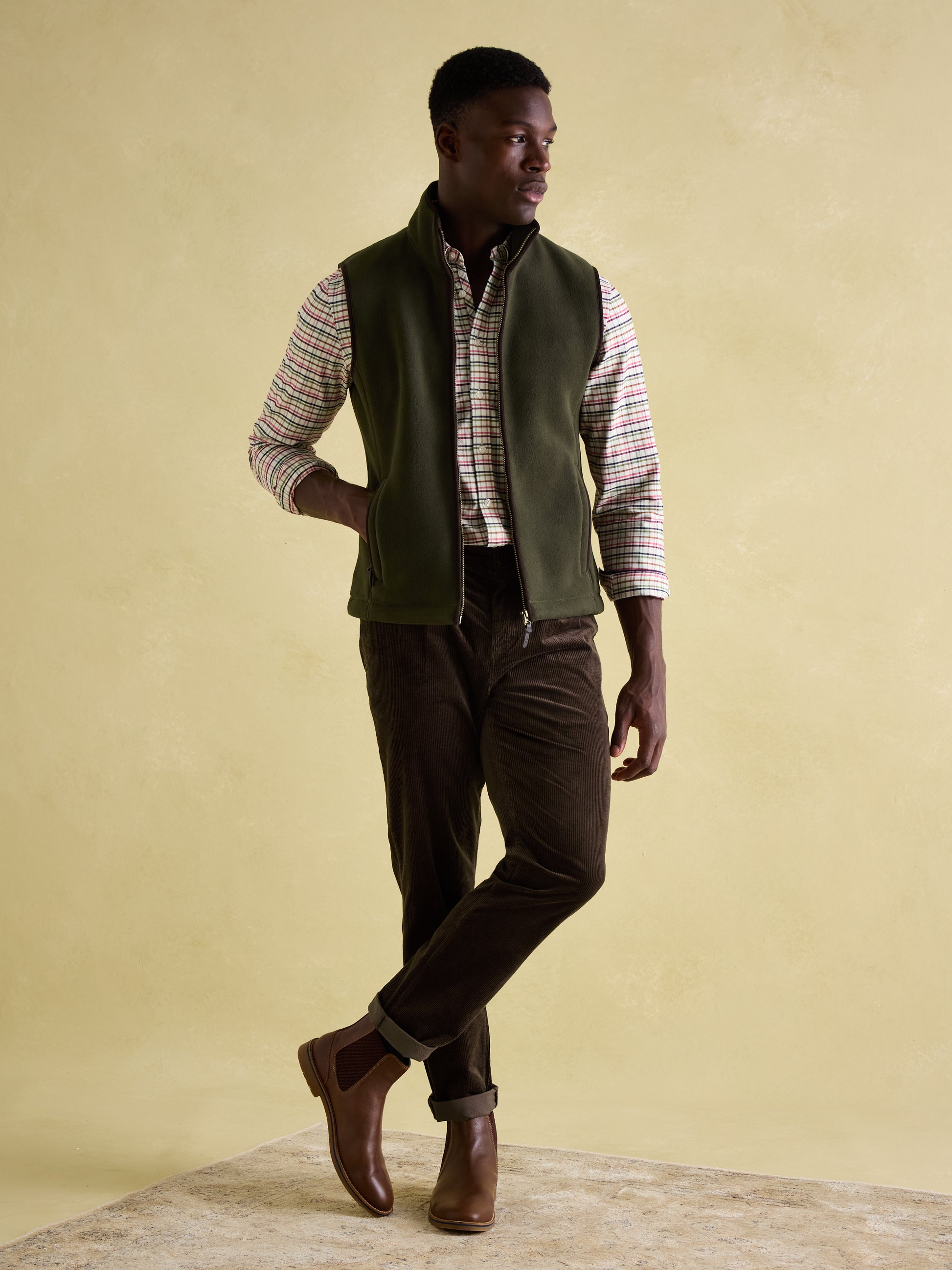 Joules GREENFIELD Mens Gilet Green front view on model, styled with checkered shirt and brown pants.