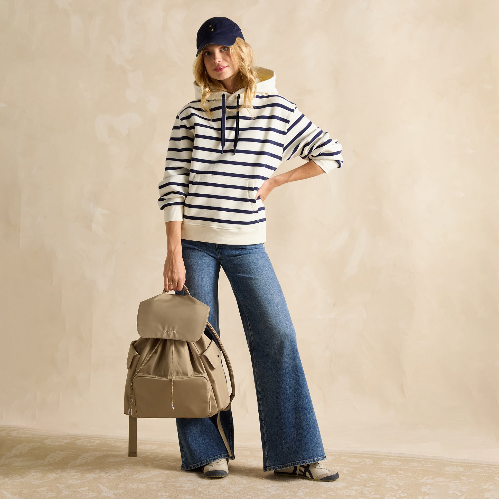 Joules CAMBECK NYLON RUCKSACK Womens NEUTRAL side view on model, styled with striped hoodie and flared jeans.