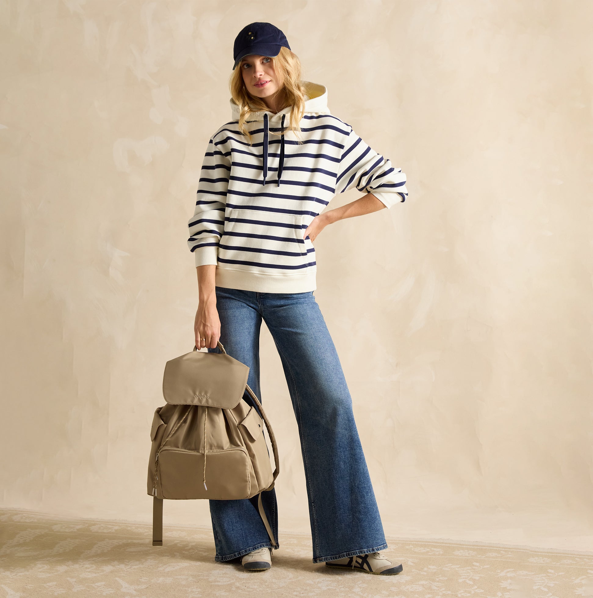 Joules CAMBECK NYLON RUCKSACK Womens NEUTRAL side view on model, styled with striped hoodie and flared jeans.