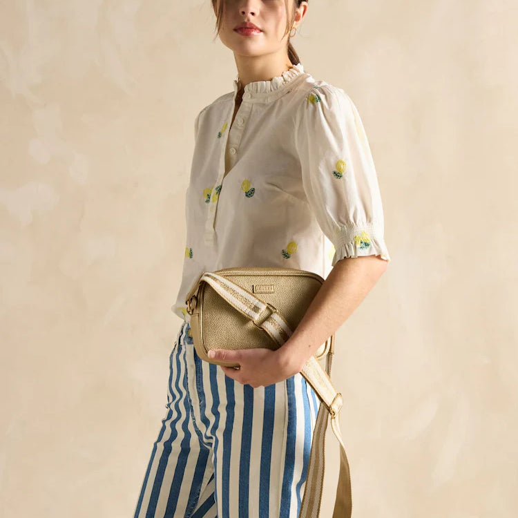 Joules TRENT Womens Cross Body Bag Gold worn by model, side view showing adjustable strap and zip closure.