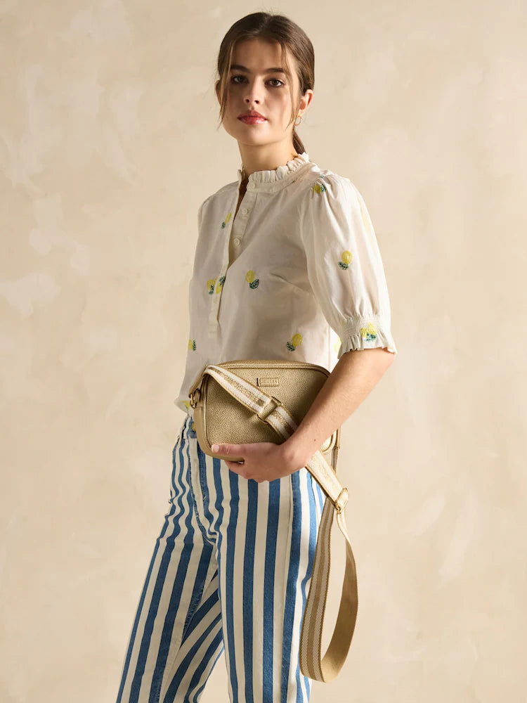 Joules TRENT Womens Cross Body Bag Gold worn by model, side view showing adjustable strap and zip closure.