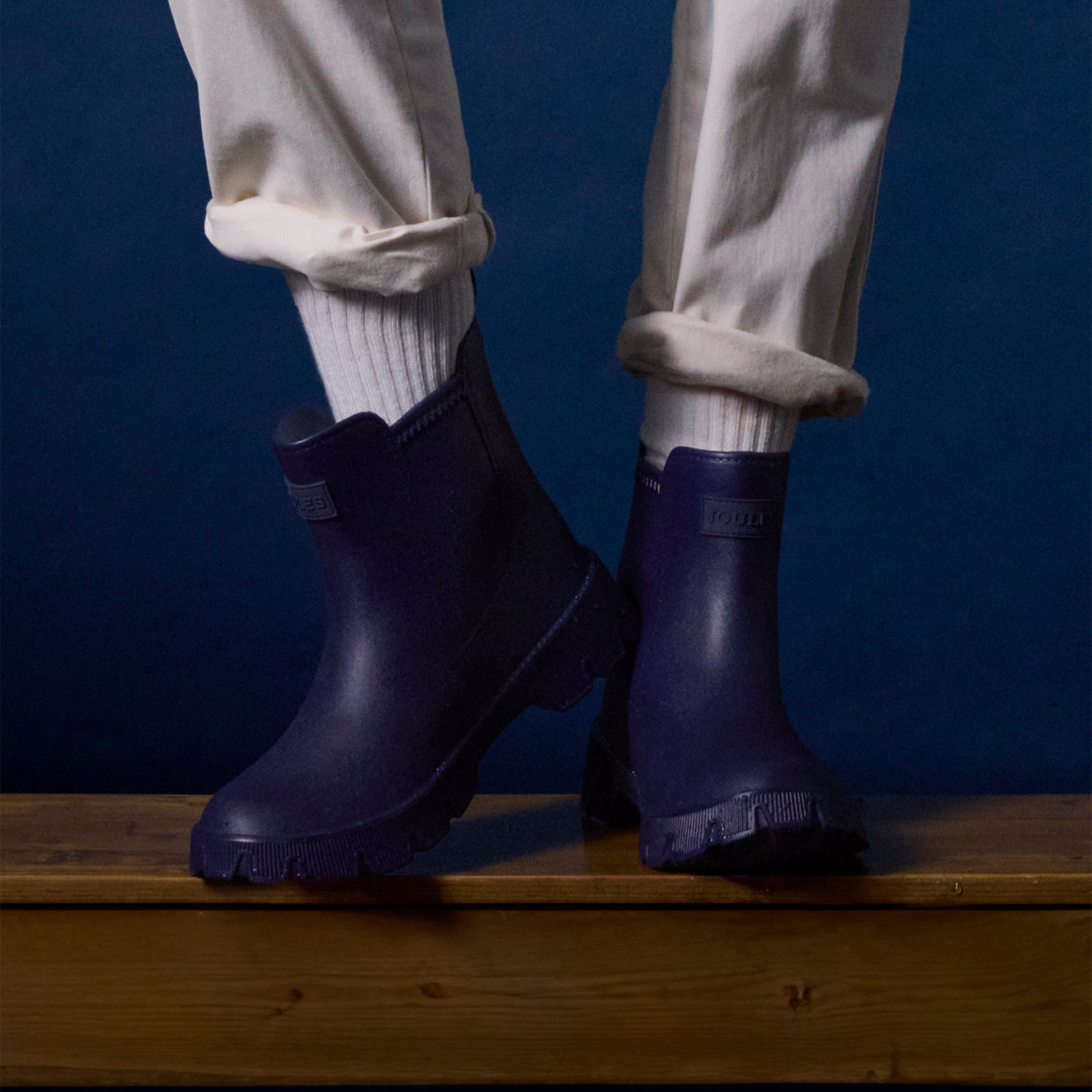 Joules RAINDANCE Lightweight Wellies Navy side view on a person standing on wooden surface with light clothing.