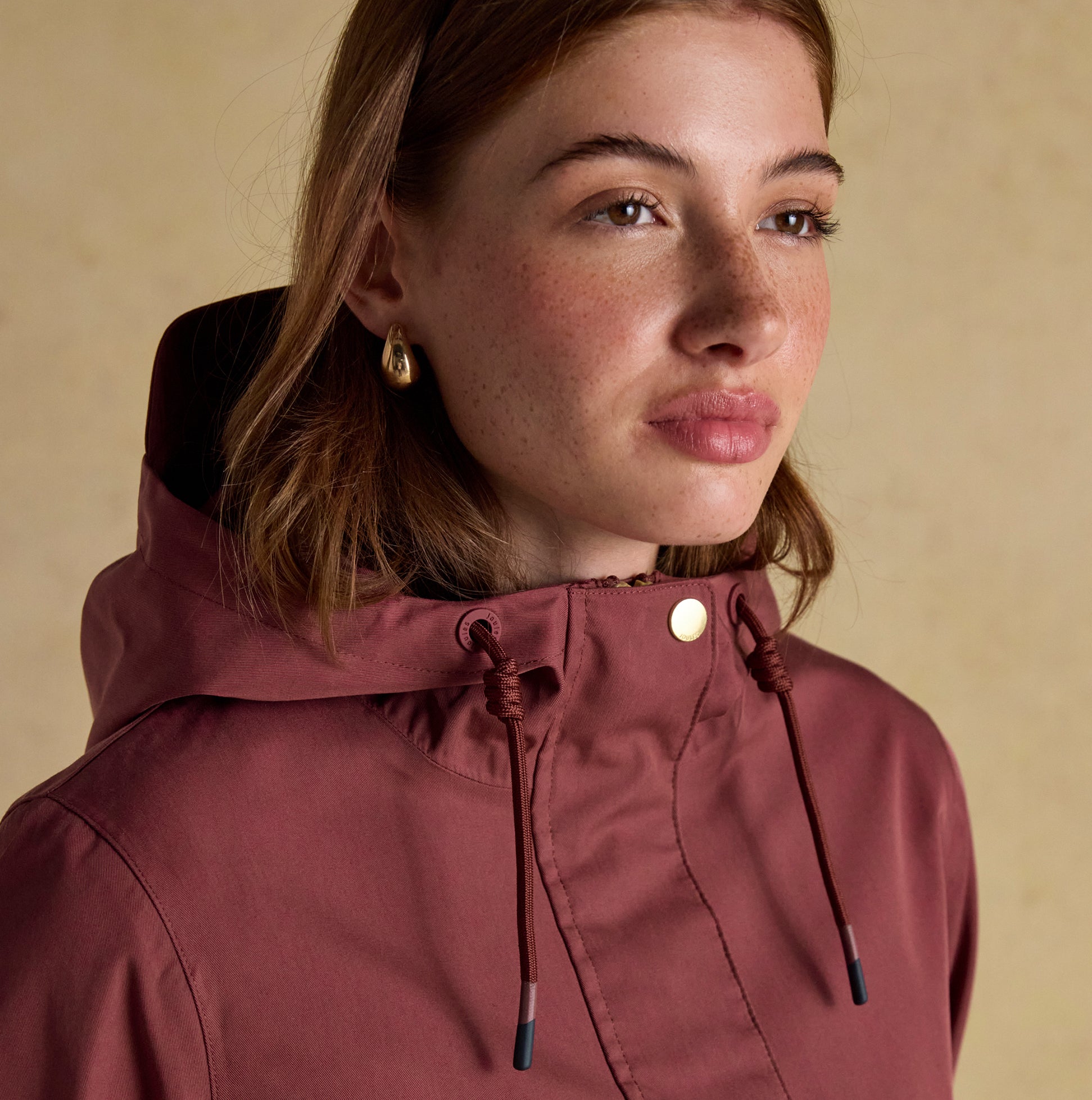 Joules PORTWELL Waterproof Hoodie Raincoat With Adjustable Waist Oxblood close-up view of model wearing hoodie with adjustable waist.