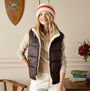 Joules POPLEY STRIPE Womens Beanie Orange/Neutral front view worn by model with brown vest, smiling in cozy indoor setting.