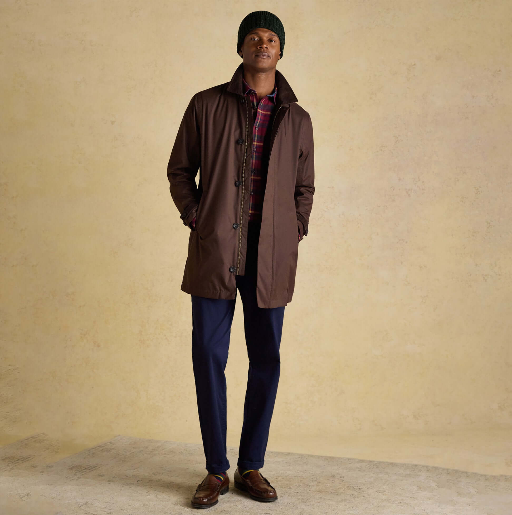 Joules HAMMOND Mens Beanie Green worn with brown coat, front view on model, styled with plaid shirt and blue trousers.