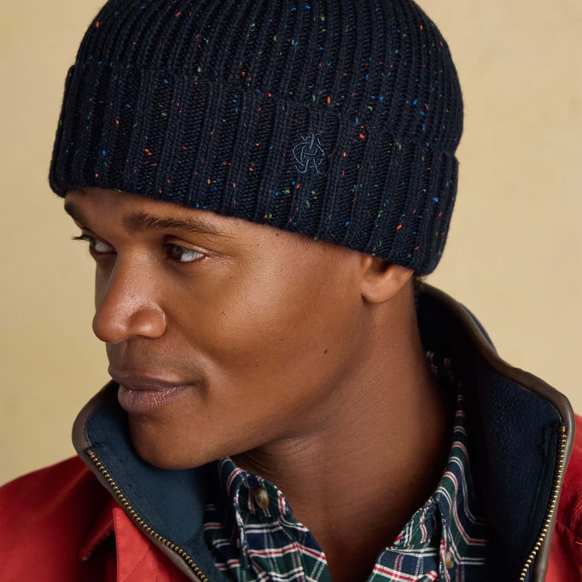 Joules HAMMOND Mens Beanie Navy side view on model, showcasing textured knit and playful speckles.