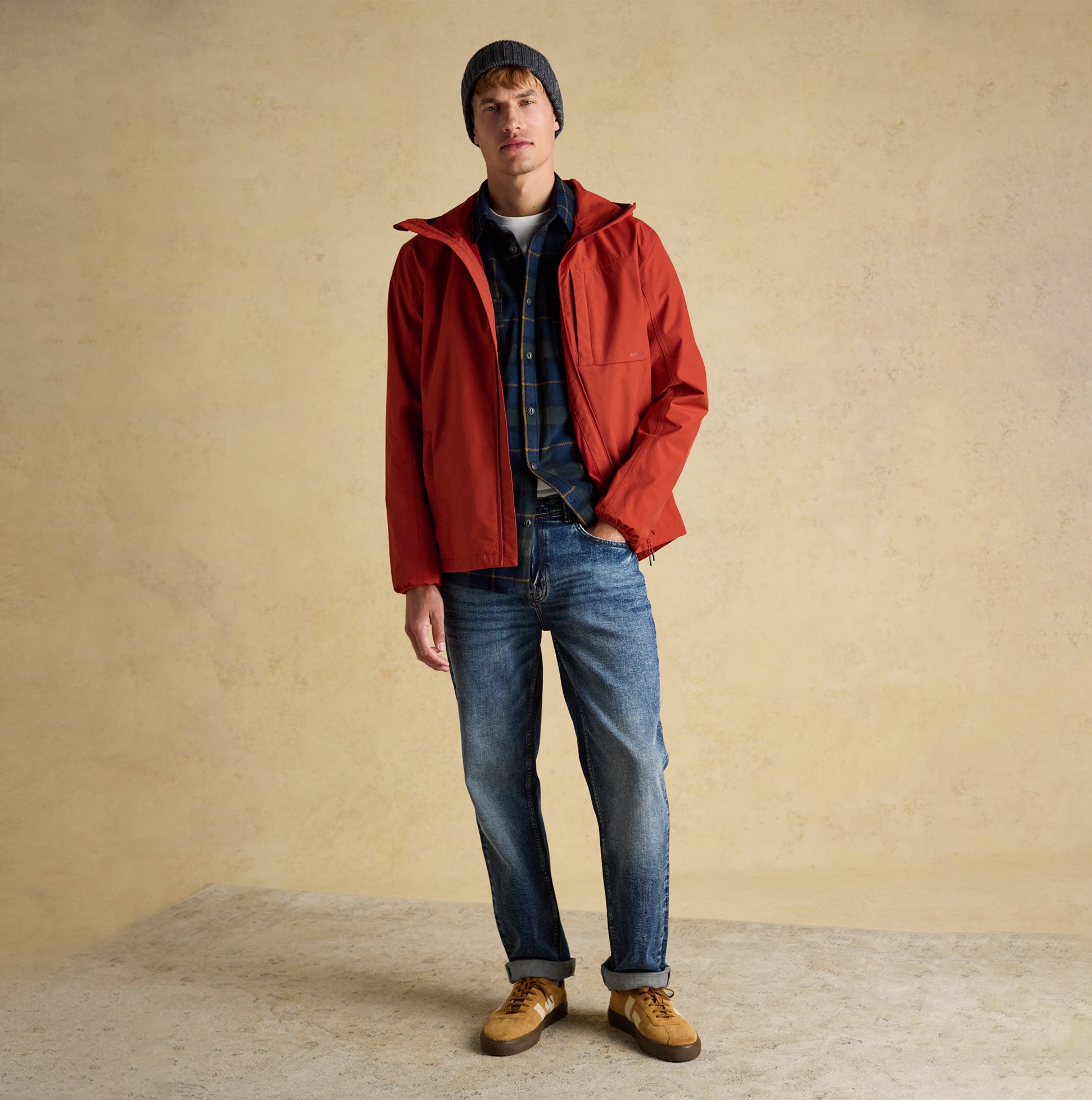 Joules HAMMOND Mens Beanie Grey worn by a man in a front view, paired with a red jacket and denim jeans.