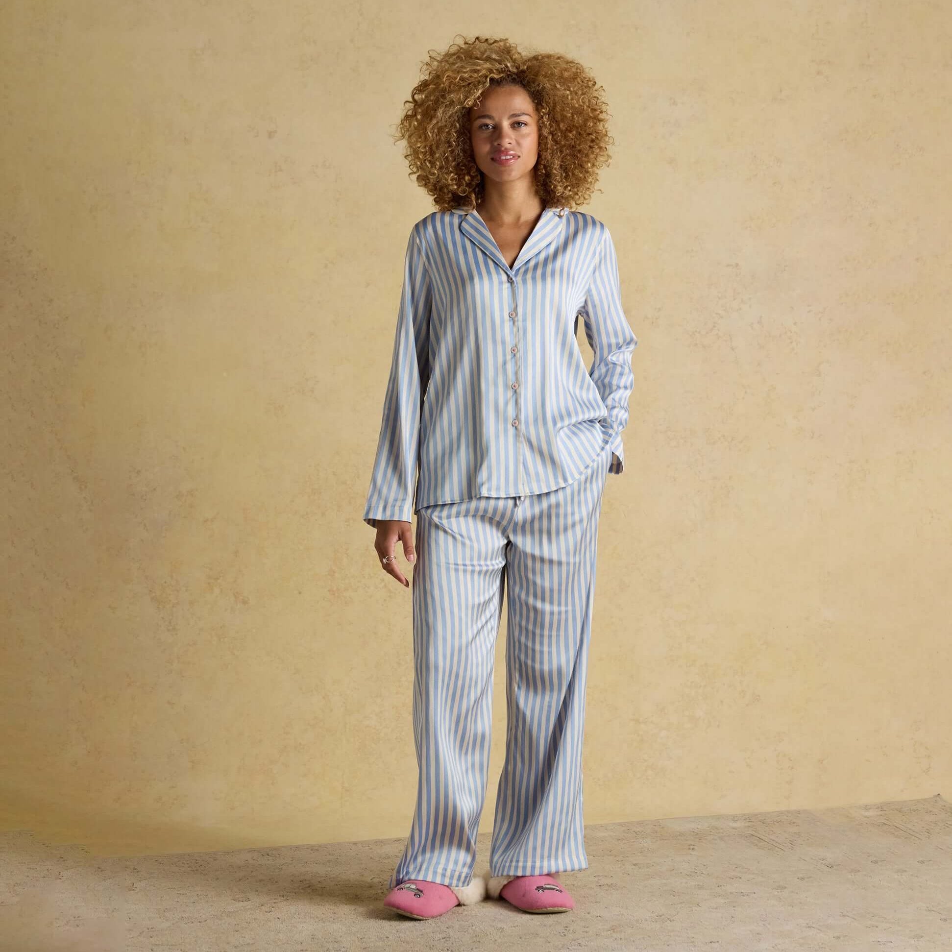 Joules BONNIE Womens Satin Pyjama Set Blue Stripe front view model wearing set with curly hair on beige background.