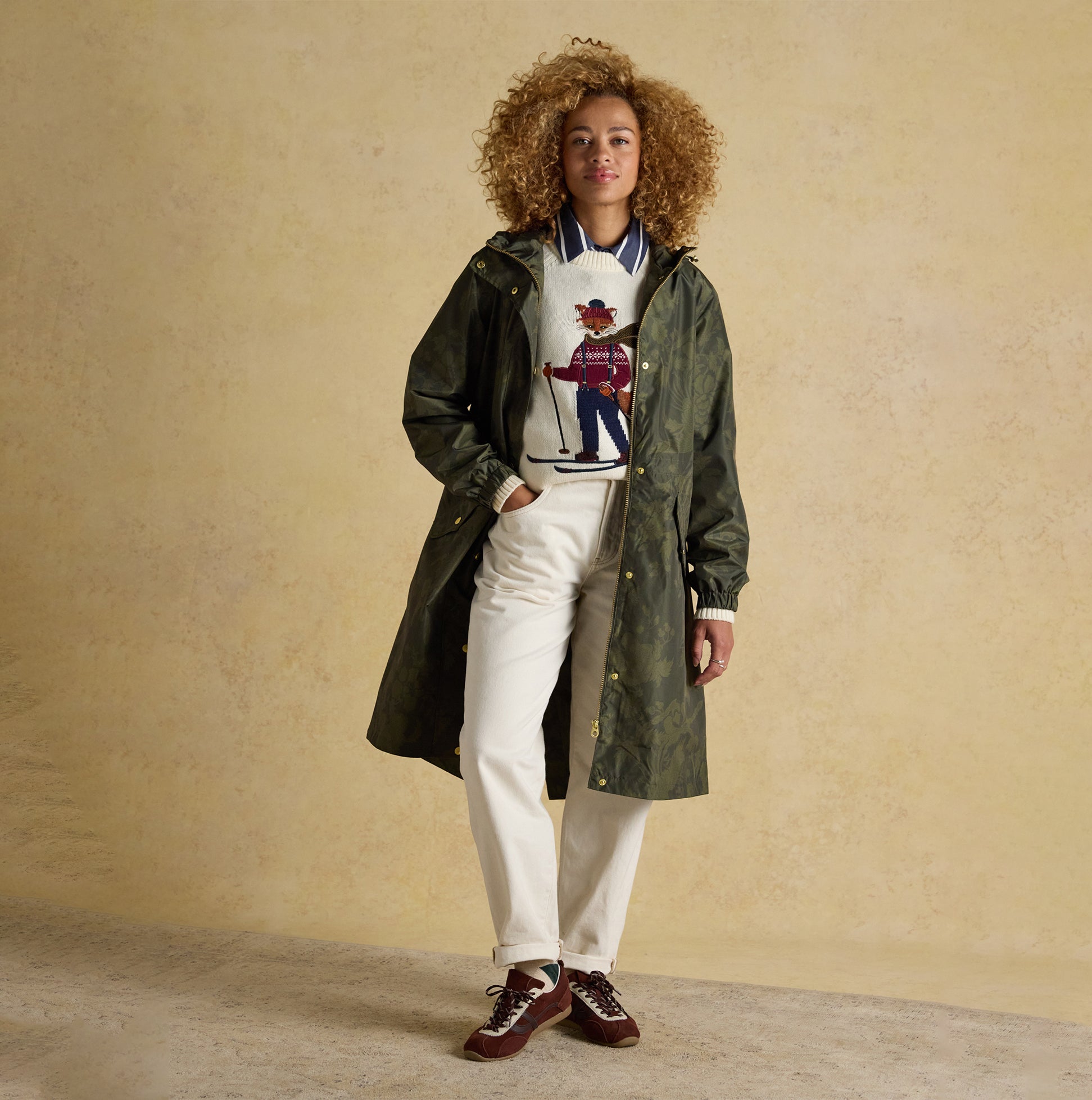 Joules HOLKHAM Waterproof Packable Raincoat With Hood Green front view on model, styled with sweater and pants.