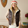 Joules REVERSIBLE FUR Faux Fur Padded Gilet Brown/Cream front view on model with knit hat, elegantly styled in indoor setting.