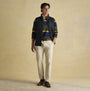 Joules MAYNARD Mens Gilet Navy front view worn over a striped shirt, complemented with cream trousers and brown shoes.