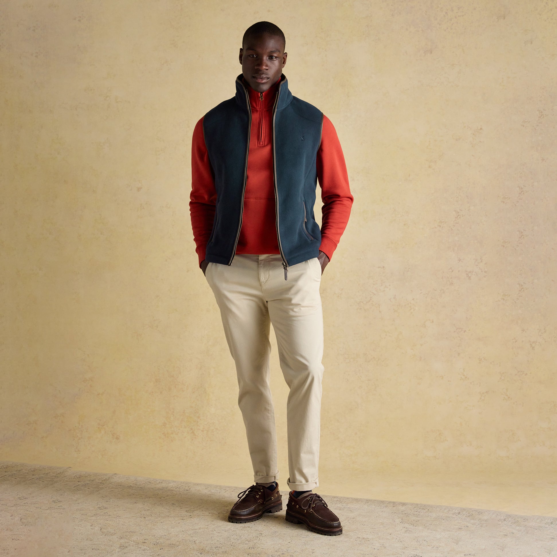 Joules HERITAGE FLEECE Mens Gilet Navy front view worn by a model, paired with a red top and light pants.
