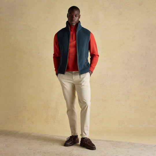 Joules HERITAGE FLEECE Mens Gilet Navy front view worn by a model, paired with a red top and light pants.
