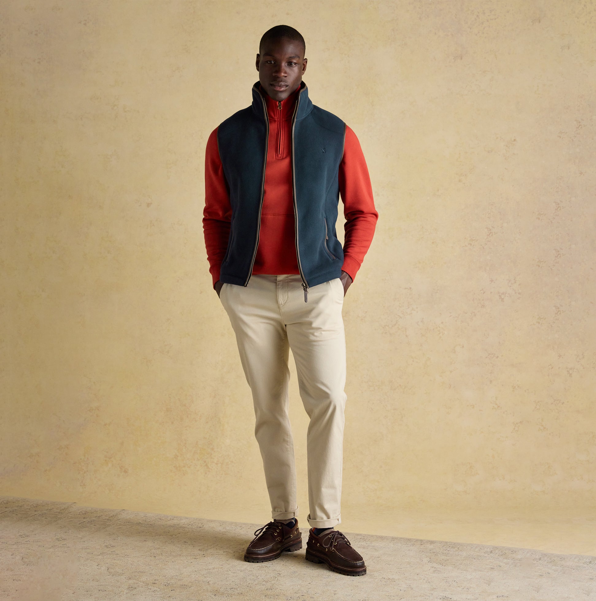 Joules HERITAGE FLEECE Mens Gilet Navy front view worn by a model, paired with a red top and light pants.