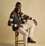 Joules HERITAGE FLEECE Mens Gilet Green front view on model, styled with colorful striped shirt and seated on chair.
