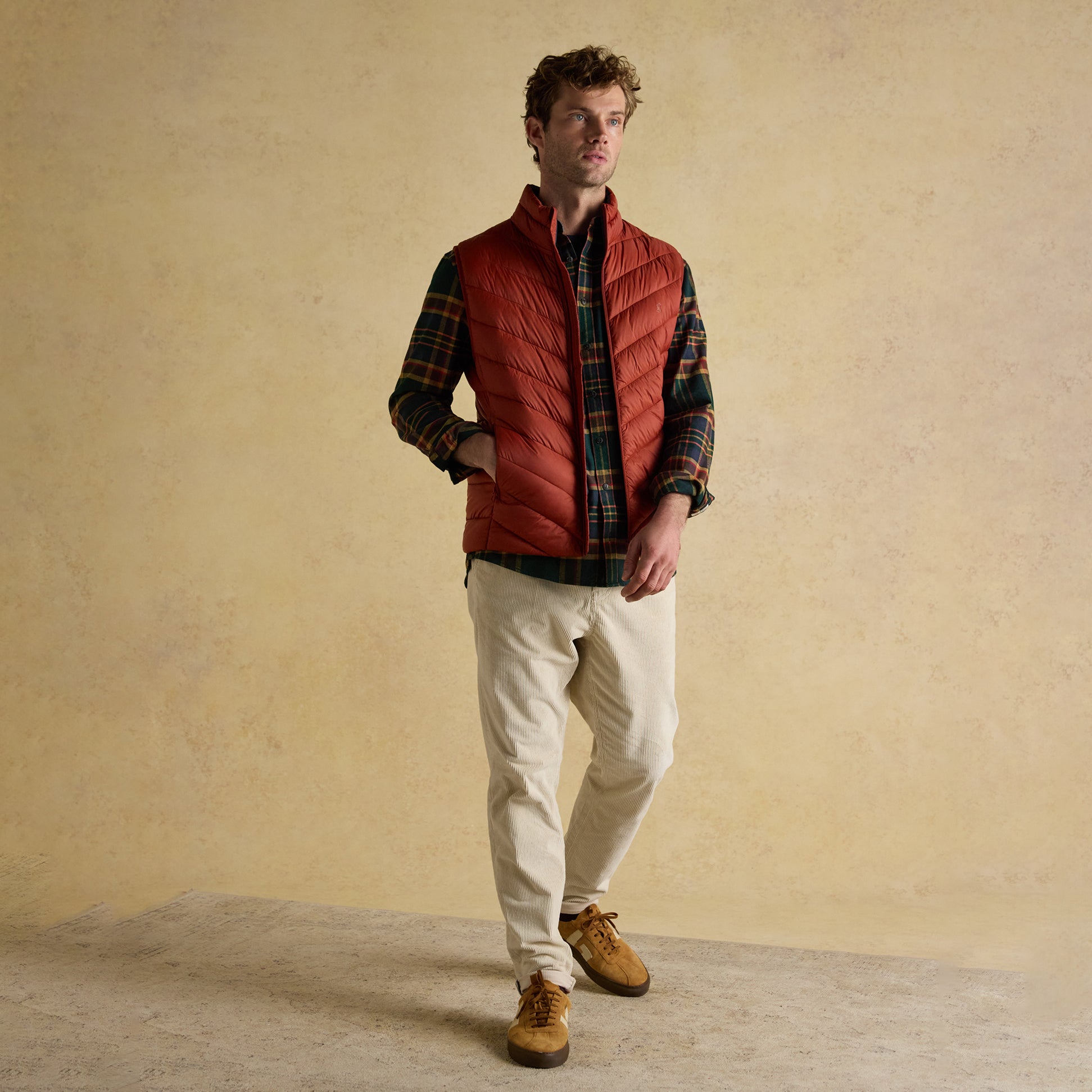 Joules GARRETT Mens Showerproof Padded Gilet Orange front view worn by man with plaid shirt and cream trousers.